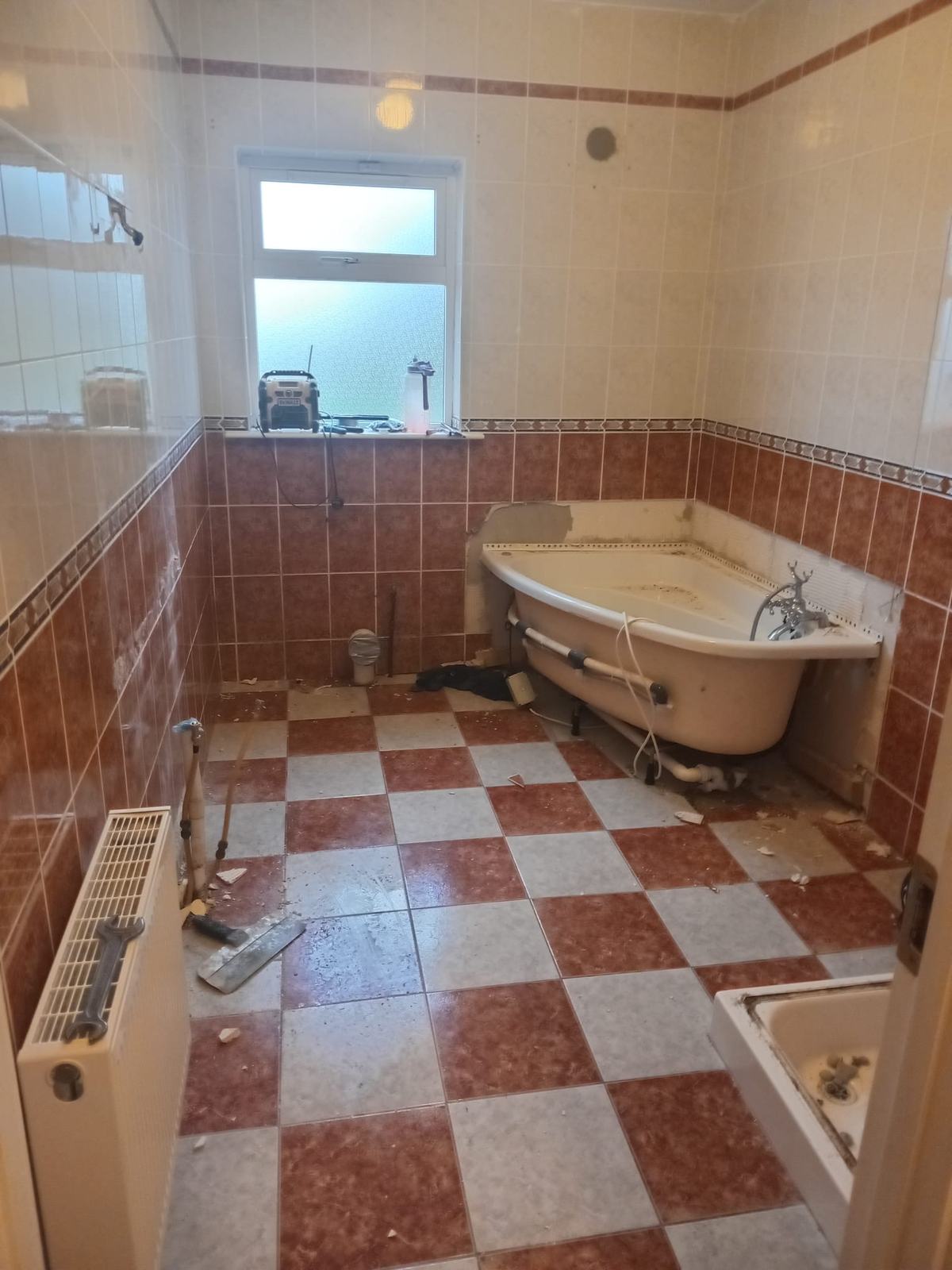 Before: dated 1990s bathroom with terracotta and cream tiles and a corner bath