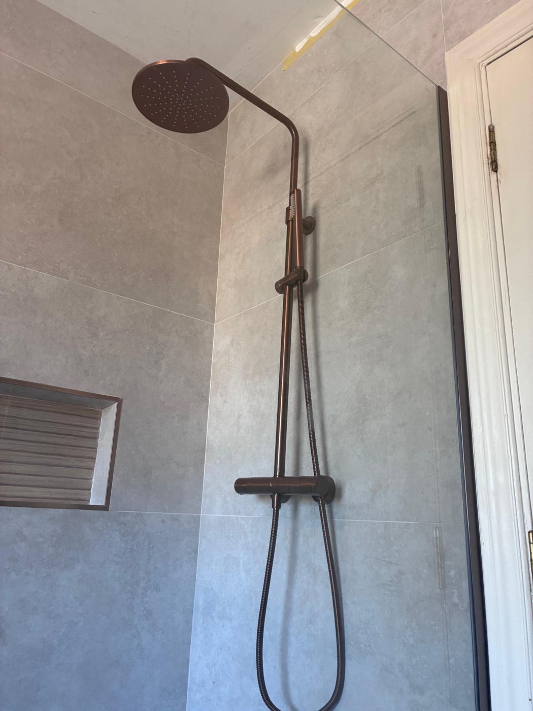 Brushed copper rainfall shower on grey stone-effect tiles
