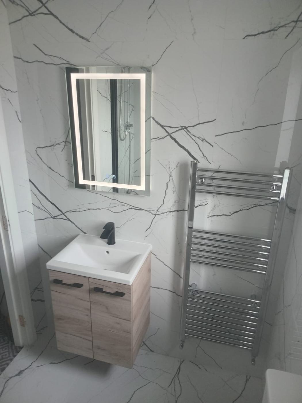 Grey-vein marble bathroom with oak vanity and chrome towel rail