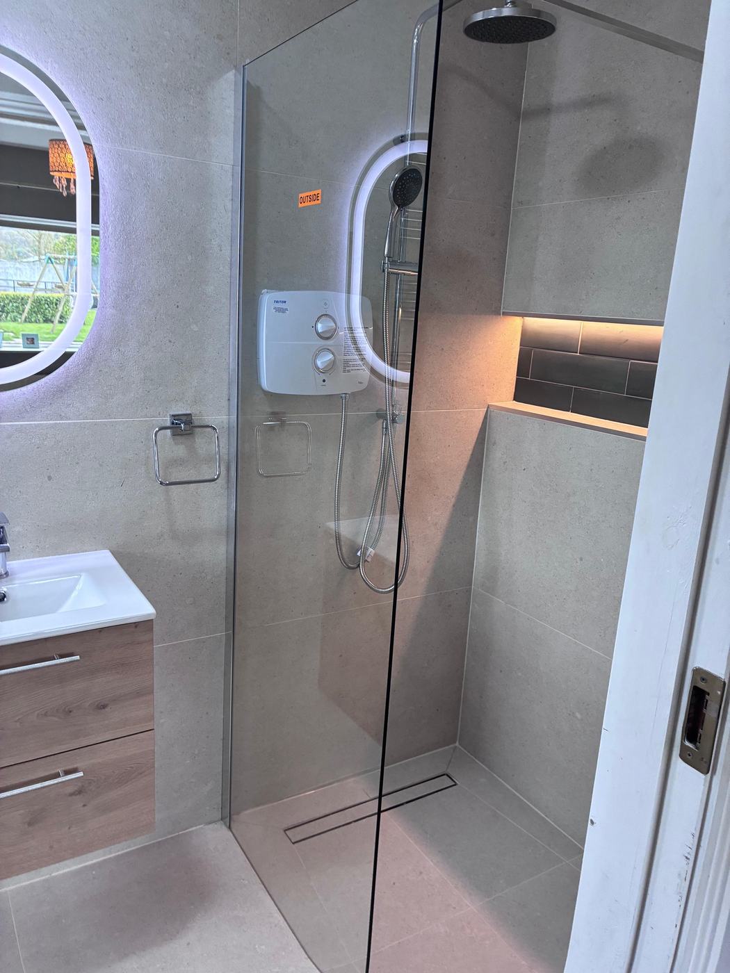 Walk-in shower with linear drain and LED-lit niche